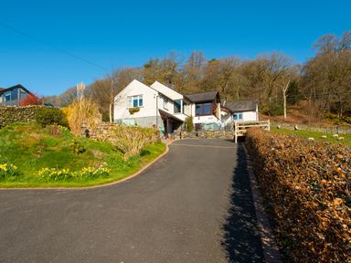 A driveway leading to a white house with stone walls and surrounding greenery at Browside in Little Arrow near Coniston