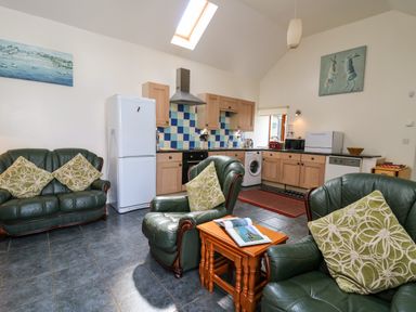 A kitchen and seating area with green leather chairs and wooden cabinets at Yr Hen Ysgubor in Trelech near St Clears
