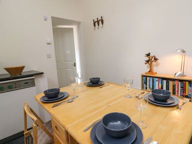 A dining table set for four with blue dishes and wine glasses in a room with a bookshelf decorated with sculpture at Yr Hen Ysgubor in Trelech near St Clears