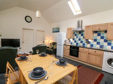 A kitchen and dining area with a wooden table set for four and seating at Yr Hen Ysgubor in Trelech near St Clears