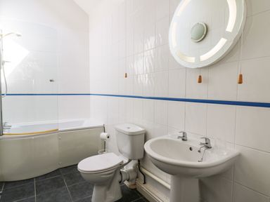 A bathroom with a bathtub shower toilet sink and circular mirror at Yr Hen Ysgubor Trelech near St Clears
