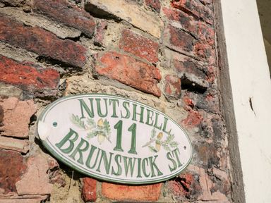 An oval house sign on a brick wall with the text Nutshell 11 Brunswick St at Nutshell in Whitby