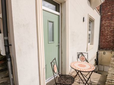 An outdoor area with a green door a small round table and two chairs with tiled tops at Nutshell in Whitby
