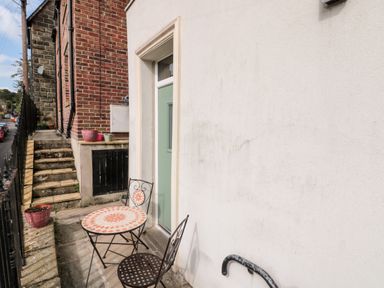 A small outdoor patio area with a round table and two chairs next to a green door at Nutshell in Whitby