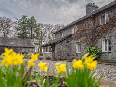 A stone house and an outbuilding with yellow flowers in the foreground at Crabtree in Hawkshead