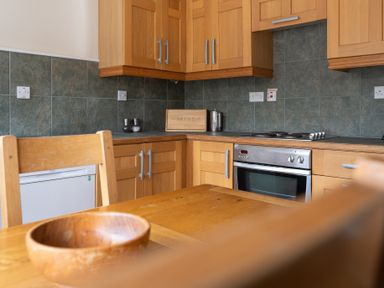 A kitchen with wooden cabinets a wooden table and chairs a bread box and an oven at Crabtree in Hawkshead