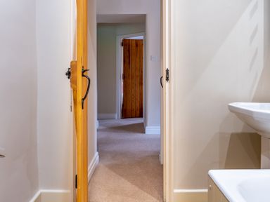 A hallway with wooden doors and a white sink visible in a bathroom at Crabtree in Hawkshead