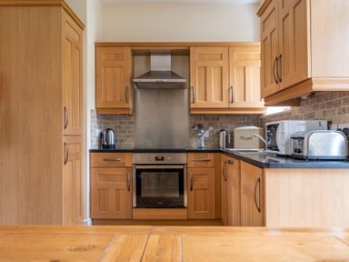 A kitchen with wooden cabinets a stainless steel oven kettle toaster and microwave at Forge in Graythwaite near Hawkshead