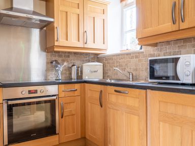 A kitchen with wooden cabinets a stainless steel oven microwave and sink at Forge Graythwaite near Hawkshead