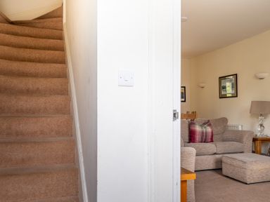 A carpeted staircase next to a living room with a sofa and pouf at Forge in Graythwaite near Hawkshead