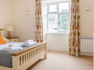 A bedroom with a bed with folded towels on it next to a window with curtains at Forge Graythwaite near Hawkshead