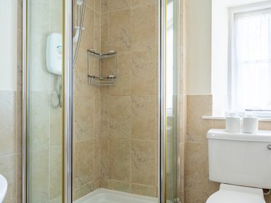 A bathroom with a shower enclosure and a toilet with two rolls of toilet paper on the cistern at Forge Graythwaite near Hawkshead