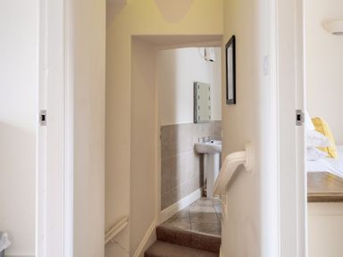 A hallway with stairs leading to a small bathroom with a sink and mirror at Forge Graythwaite near Hawkshead