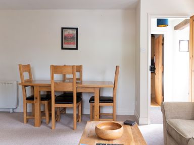 A dining area with a wooden table and four chairs and a framed picture on the wall at Newlands Graythwaite near Hawkshead