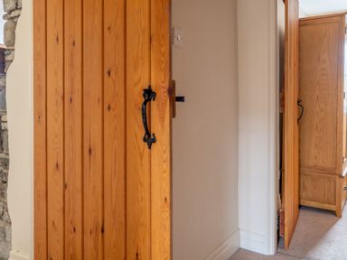 A wooden door partially open revealing a glimpse of a wooden wardrobe in a room at Newlands Graythwaite near Hawkshead