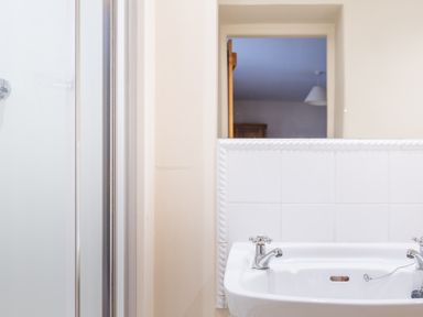 A bathroom sink with two taps and a shower enclosure on the side at Newlands in Graythwaite near Hawkshead