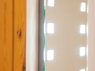 A close up of a wooden door frame and a frosted glass panel with square light patterns at Newlands in Graythwaite near Hawkshead