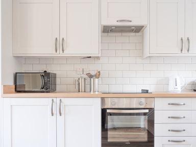 A modern kitchen with white cabinets a microwave an oven a kettle and cooking utensils at Greenhowes in Graythwaite near Hawkshead