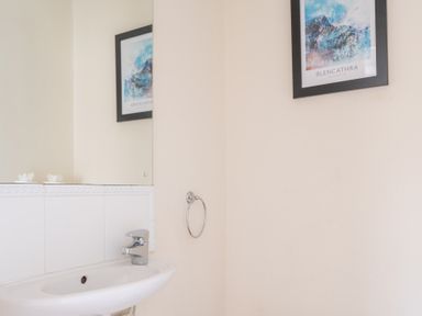 A bathroom sink with a faucet a mirror above and a framed picture on a wall at Greenhowes Graythwaite near Hawkshead