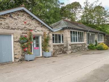 A stone building with blue doors and windows surrounded by plants at Jubilee in Graythwaite near Hawkshead