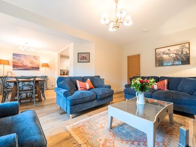 A living room with sofas, a coffee table, and a dining area at Jubilee at the Graythwaite Estate Graythwaite near Hawkshead