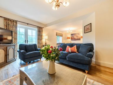 A living room with a sofa, coffee table, and TV at Jubilee at the Graythwaite Estate near Hawkshead