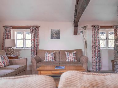 A living room with sofas cushions wooden coffee table and patterned curtains at Lords Leap Graythwaite near Hawkshead