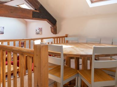 A dining area with a wooden round table and chairs under a sloped ceiling with a skylight at Lords Leap Graythwaite near Hawkshead