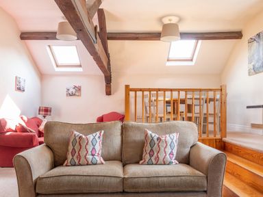 A living room with a beige sofa and patterned cushions wooden beams and skylights at Lords Leap in Graythwaite near Hawkshead