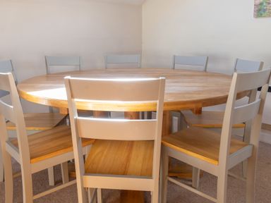 A round wooden dining table surrounded by eight wooden chairs in a room at Lords Leap in Graythwaite near Hawkshead