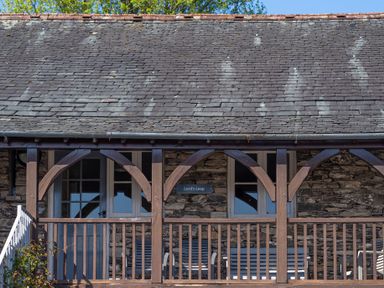 A stone building with a slate roof wooden balcony and windows at Lord's Leap in Graythwaite near Hawkshead