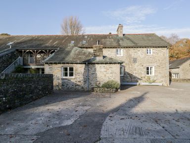 A stone house with multiple windows and a concrete driveway at Bassicks in Hawkshead