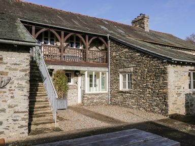 Exterior view of a stone house with an outdoor staircase and a covered balcony at Bassicks in Hawkshead