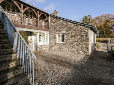 An exterior view of a stone house with stairs on the left and a gravel pathway at Bassicks in Hawkshead