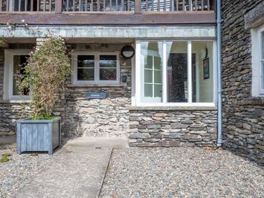 Stone building exterior with windows wooden planter and gravel ground at Bassicks in Hawkshead