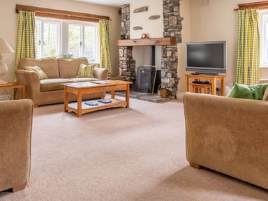 A living room with sofas coffee table fireplace and television at Bassicks Hawkshead