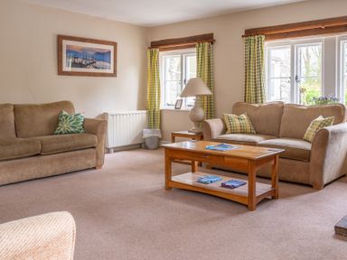 A living room with two sofas a wooden coffee table and green patterned curtains at Bassicks Hawkshead