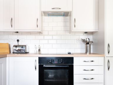 A kitchen with white cabinets a black oven a toaster salt and pepper shakers and utensils at Bassicks Hawkshead
