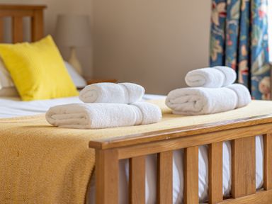 A bed with folded white towels and a yellow pillow in a bedroom at Bassicks in Hawkshead