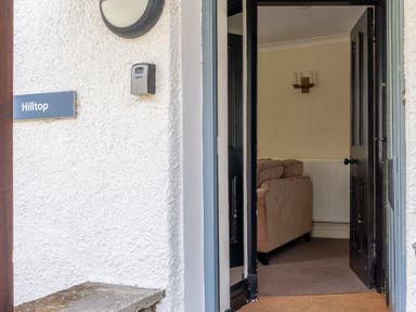 An open black door showing part of a beige sofa and radiator inside Hilltop in Graythwaite near Hawkshead
