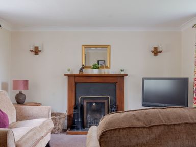 A living room with a fireplace a television and sofas at Hilltop in Graythwaite near Hawkshead