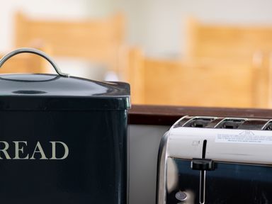 A close-up of a black bread box and a silver toaster on a kitchen counter
