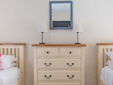 A bedroom with two beds on either side of a chest of drawers with two lamps and a mirror above the chest at Hilltop in Graythwaite near Hawkshead