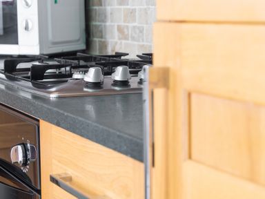A kitchen countertop with a gas stove and oven with wooden cabinets at Mill Cottage in Graythwaite near Hawkshead