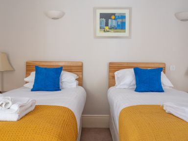 A bedroom with two single beds with blue cushions and yellow throws at Mill Cottage in Graythwaite near Hawkshead