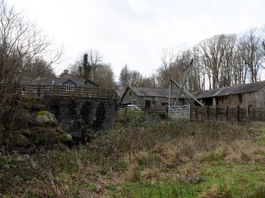 Stone buildings and wooden fences with leafless trees in the background at Mill Cottage in Graythwaite near Hawkshead
