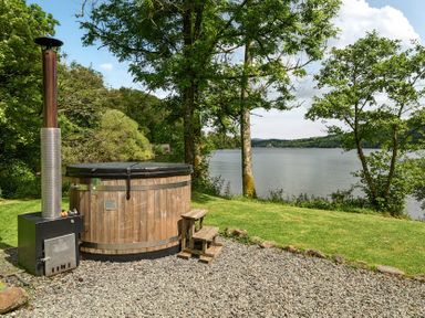 A hot tub with a wooden structure beside a lake at Hullet Hall at the Graythwaite Estate near Hawkshead