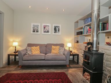 A living room with a sofa, lamp, and stove at The Stable in Deepdean near Ross-on-Wye