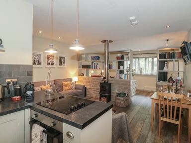 A living room with a couch and bookshelf at The Stable in Deepdean near Ross-on-Wye