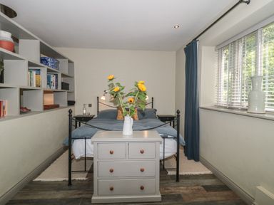 A bedroom with a bed and shelf with books at The Stable Deepdean near Ross-on-Wye
